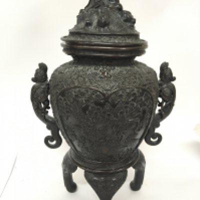 A large Chinese 19th century bronze vessel the cover in the form of a seated elder the profusely decorated sides with raised dragons on four shaped feet (one foot detached cover edge slightly miss shape. No obvious caricature marks. Height 55cm