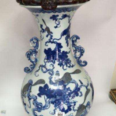 A large Chinese export porcelain blue and white floor vase decorated with animals amongst grape vines the sides with raised handles and the top with a carved wood cover some repair to the rim. 98cm high.