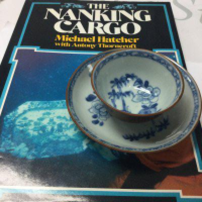 A Nanking Cargo tea bowl and saucer. Together with the book by Michael Hatcher .
