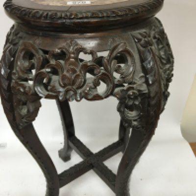 A Chinese carved hardwood jardiniere stand the round top inset with marble with a carved apron and legs United by stretchers. Height 61cm