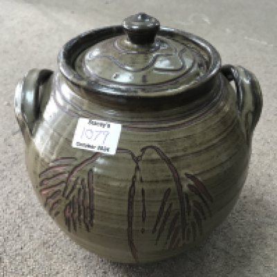 A jar and cover with raised side handles, dark green glaze incised decoration and impressed potters mark. 250cm