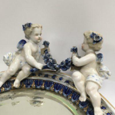 A Dresden Porcelain oval mirror with raised cherubs flowers and foliage. 33 cm .