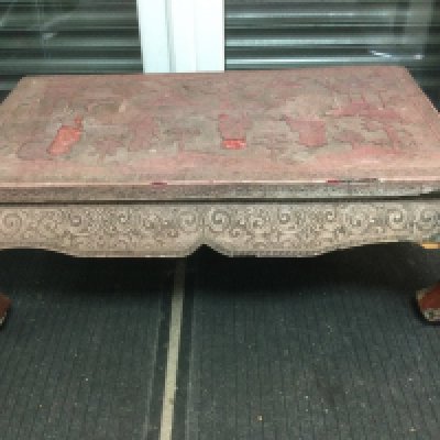 A highly decorative cinnabar low table, top diameter approx 90cm. Some damage. Shipping category D.