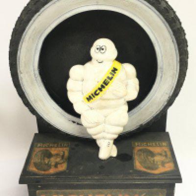 A Michelin advertising figure sitting in a tyre and on a wooden base advertising tyres and tubes, 42cm tall. Postage category C