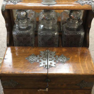 A late Victorian Oak Tantalus with three cut glass decanters, locking case system, storage compartments and key. Case dimensions 26x37x32cm. This lot cannot be posted