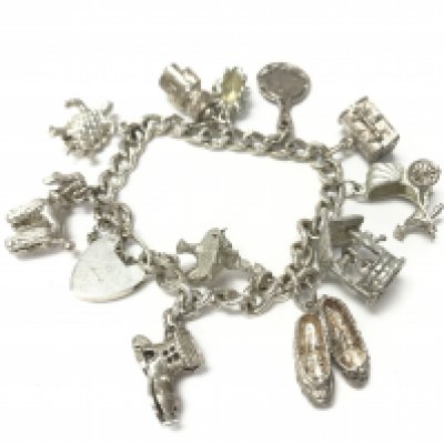 A silver charm bracelet with a large number of charms. 60.28g. Postage B