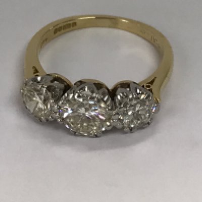 A 18 ct gold ring inset with three brilliant cut diamonds the centre diamond approximately 1.5ct flanked by two further diamonds 0.80ct colour K clarity SI .