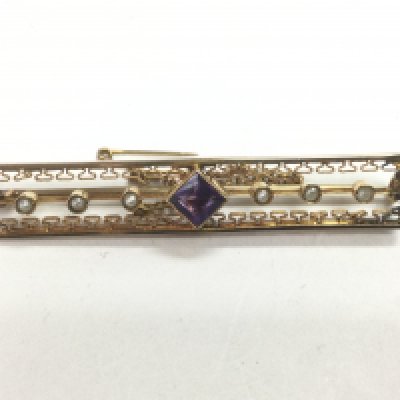 A circa 1920s unmarked gold brooch set with a central amethyst and six small pearls, approx 3.9g. Shipping category A.