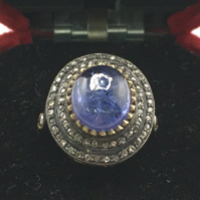 A cabochon tanzanite and diamond cluster ring. Tanzanite 5.38ct, diamonds 0.52Ct. Size Q. Postage category a