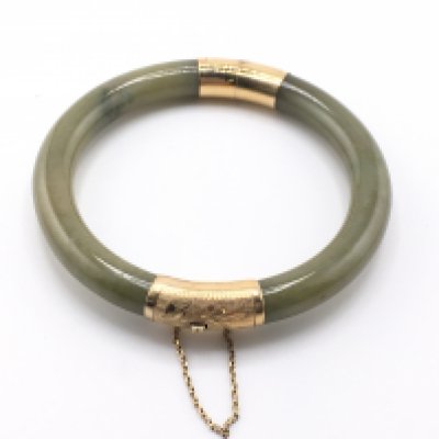 A jade bangle with 14k gold mounts. Approximately 7cm diameter.Postage A
