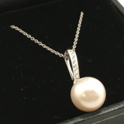 A 9 carat white gold round freshwater pearl and diamond pendant on a 9ct white gold chain. Diamonds 0.07ct. 3.3g total weight. Postage category a