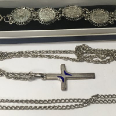A silver coin bracelet together with cross and chain and one other chain .
