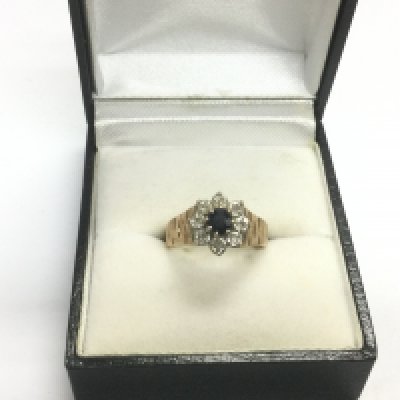 A 9ct gold ring set with a central sapphire surrounded by diamonds, approx 3.2g and approx size L. Shipping category A.