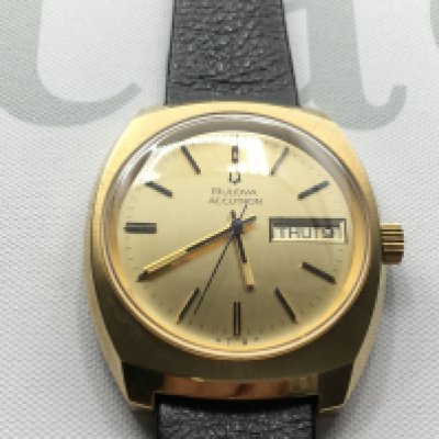 A gents Bulova Accutron day date wrist watch with gold coloured dial and black leather strap in excellent condition. Seen running. Postage B