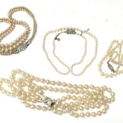 A collection of simulated pearl necklaces, one with a silver clasp.