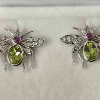 Pair of 18ct white gold large fly design earrings set with oval peridot, cabochon ruby and diamonds, boxed. Peridot 1.70ct. Rubies 0.17ct. Diamonds 0.30ct. Postage category A.