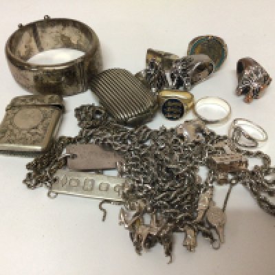 A collection of silver jewellery rings necklaces a charm bracelet a wide silver bangle vesta cases and metal rings.