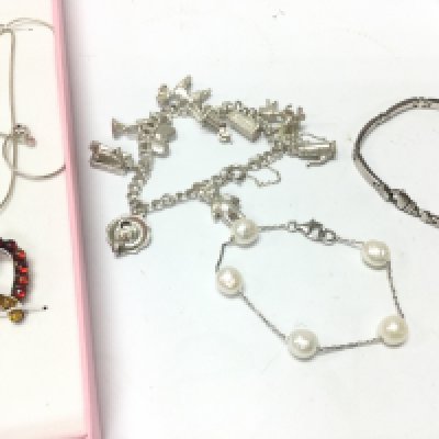 A collection of silver bracelets including a charm bracelet and a necklace with Amber pendant