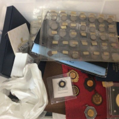 A plastic tub containing commemorative coins used circulated coins a gold 585 half gram coin and others.