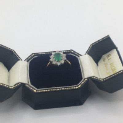 A quality 18carat gold ring set with an emerald flanked by a pattern of brilliant cut diamonds.the emerald approximately 10x7mm each diamond approximately 0.12. Total weight 5g ring size N-O
