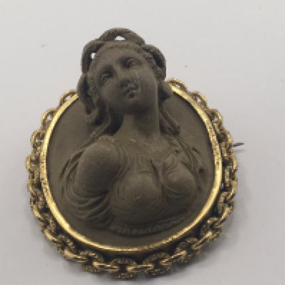 A carved Italian 19th Century Grand Tour carved volcanic rock brooch with high relief lava carving the form of a bust of a Neo classic lady.