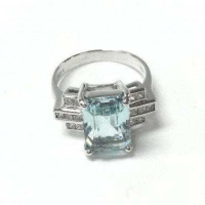 An 18ct white gold dress ring set with step cut aquamarine flanked by princess cut diamonds. Aquamarine 3.87ct and diamonds 0.38ct approximately. Size N 1/2 and 5.5g