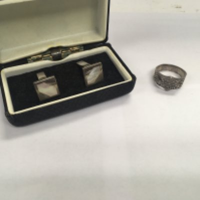 A silver pair of cufflinks and a silver Harley Davidson motorcycles ring.