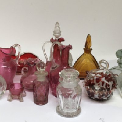 A collection of cranberry glass scent bottles and other glass.