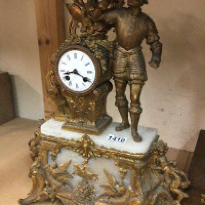 A gilt metal mantle clock of classical influences the enamel dial with Roman Numerals flanked by a solider.