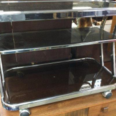 A three tier chrome trolley inset with glass tops on casters . 83cm x 44 cm .