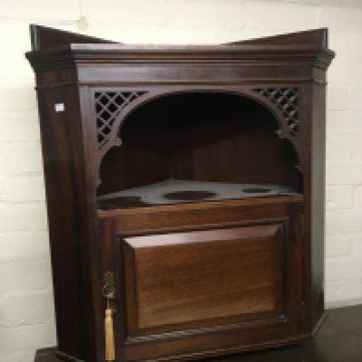 An Edwardian Mahogany corner cabinet with open fretwork corners above a door with key. 68cm