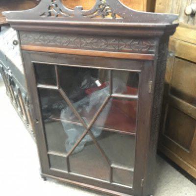 An Edwardian hanging display corner cabinet with blind fretwork and a glazed door.