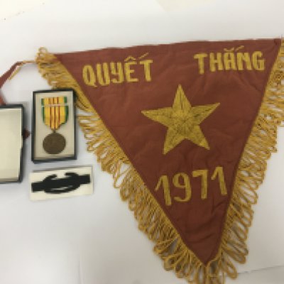 An American Vietnam war medal and a Vietnamese 1971 embroidered pennant.