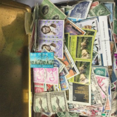 A box containing world and GB stamps in tins .