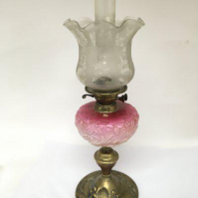 An Art nouveau glass and brass oil lamp with a pink glass reservoir and acid etched shade.
