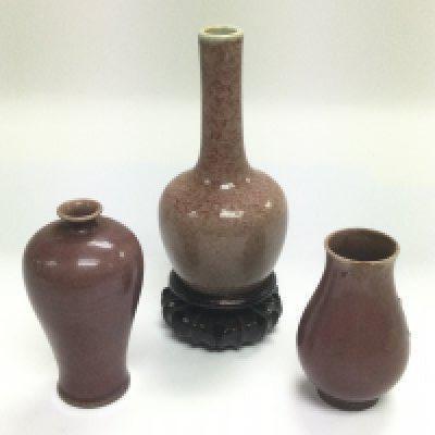 Three purple coloured bud vases, the largest being raised on a carved hardwood base, approx total height 14cm. Shipping category D.