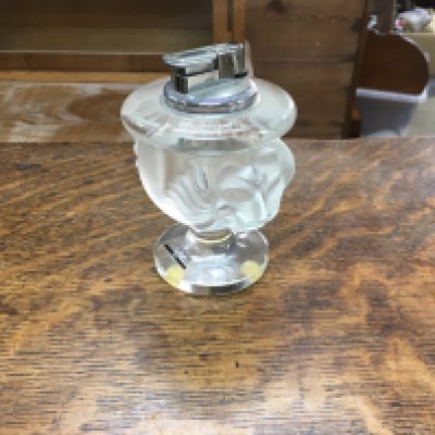 A Lalique Paris glass lighter with raised lion masks.