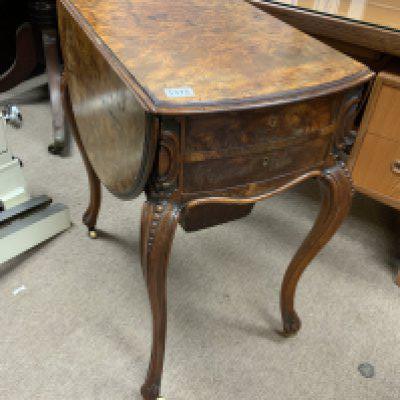 A Victorian walnut sewing table the twin flap top above cabirolet Legs on casters.