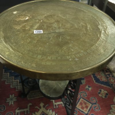 A brass occasional table the circle top with rasied elephants .