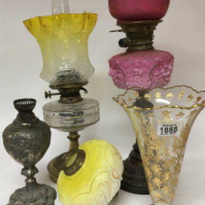 Victorian oil lamps and reservoirs including a nice fading yellow acid etched shade an acid etched cranberry shade and a vase decorated with applied gilt (damaged) and other associated oddments.