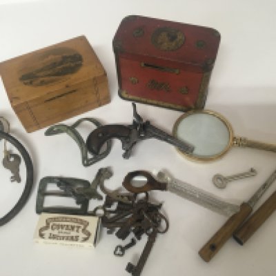 A collection of oddments vintage money boxes antique buckles keys and an Antique Belgium rim fire pocket pistol and other oddments.