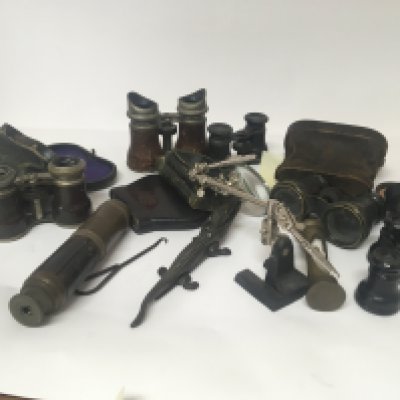 A collection of Opera glasses a telescope a magnifying glass on an adjustable stand and other oddments.