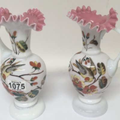 A pair of opaque enamel decorated late Victorian art glass jugs decorated with birds.