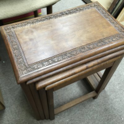 A nest of walnut tables with carved design, 46cm tall.