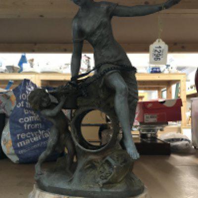A cast iron clock case in the form of a maiden and child holding basket, on a marble base