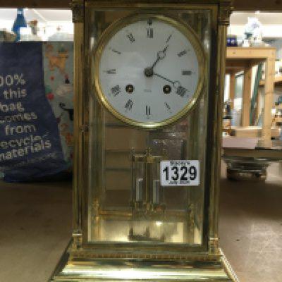 A French four glass brass mantle clock with visible mercury pendulum, the circular dial having Roman Numerals