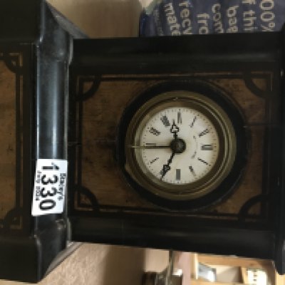 A black wooden mantle clock, the circular dial having Roman Numerals