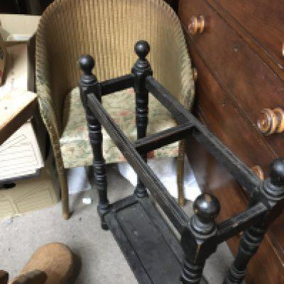 A wicker chair with floral patterned upholstery and a dark oak umbrella stand.
