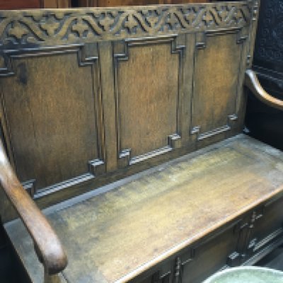 A oak settle the panel back above a lift up seat .