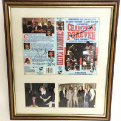 A signed Champions Forever VHS cover including signatures from Muhammad Ali, George Foreman & Joe Fraizer with photographs. This lot cannot be posted. Frame dimensions 37.5x33cm
